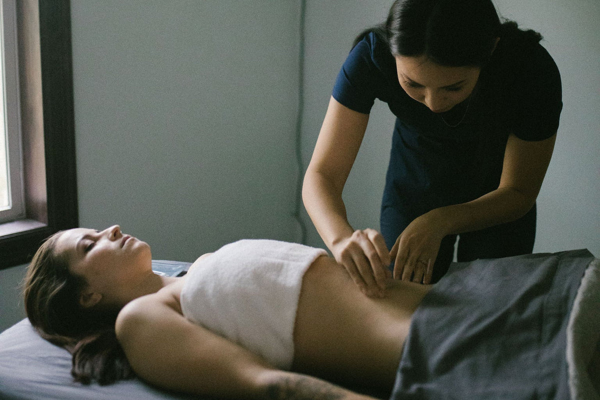 Person receiving a massage from another person in a dimly lit room.